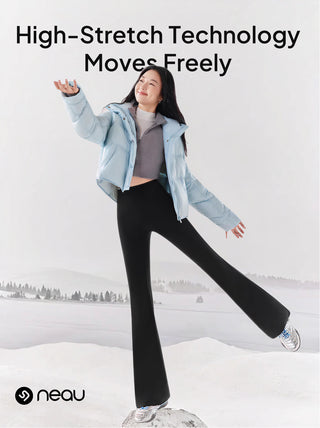 Person in light blue jacket and black pants standing in a snowy landscape with 'neau' branding.